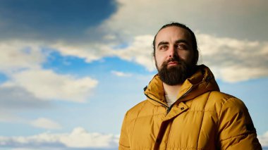 Sıcak giysili maceraperest, vahşi doğanın huzurundan, panoramik dağ manzarasından ve açık gökyüzünden keyif alır. Rahatlamak için mükemmel bir ortam yaratır. Soğuk rüzgarlar yokuş yukarı. Kamera B.