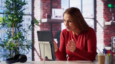 Heyecanlı bir kadın internet dersine katılıp kendi çalışma masasından yeni beceriler ediniyor, web konferansına katılıyor ve çatı katından konferans izliyor. Yetişkinler sanal eğitim sınıfına katılıyor. Kamera A.