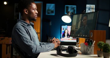 Afro-Amerikalı bir adam müdürle masa başında video konferansı yapmayı seviyor, iş arkadaşıyla internet üzerinden ofis kurulumunu kullanarak tartışmayı seviyor. Genç Ortaklar takım toplantısı online. Kamera A.