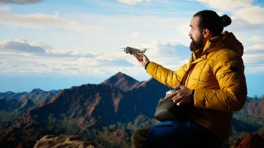 Seyahat meraklısı, insansız hava aracı görüntüleriyle onun faaliyetlerini yakalıyor. Manzaralı dağ aralığı vadisini belgeliyor. Uzaktan kumandalı güzel hava görüntüleme vlog 'u çekiliyor. Kamera A.