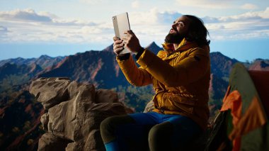 Kampçı, yüksek irtifada bir kamp alanında tablet kullanırken güçlü rüzgarla savaşıyor. Daha iyi sinyal arıyor ve güvenliğini riske atıyor. Tehlikeli dağ sıraları soğuk hava. Kamera A.