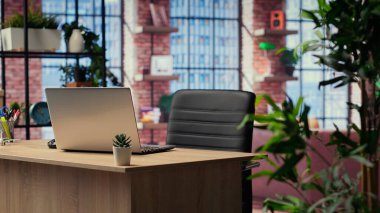 Uzak bir iş için ev ofis masası, şık mobilya ve kapalı mekan bitkileriyle dekore edilmiş modern bir apartman dairesi. Ahşap zeminli boş stüdyo alanı.