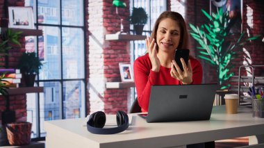 Yetişkinler, evdeki bir video görüşmesi sırasında gülümseyip el sallıyor, dijital ve kablosuz bir yaşam tarzında modern teknoloji ve çevrimiçi iletişim sergiliyor. Telefonda internet konferansı. Kamera B.