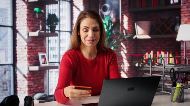 Çevrimiçi ödeme yapmadan önce bakiyeyi doğrulamak için kart numaralarını girerken gevşemiş bir kadın, internet sayfalarından alışveriş yapıyor. Web alışverişi yapan ve para transfer eden biri. Kamera B.