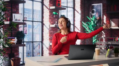 Masasında kulaklık, çalışma akışı ve modern çatı katında odaklanma müziği olan üretkenlik ile işini yaparken eğlenen olgun bir insan. Sevimli hisleri olan serbest çalışan bir kadın. Kamera B.