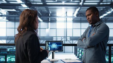 Veri merkezindeki mühendisler tablet entegre yapay zeka otomasyon araçlarıyla bakım yapıyorlar. Sunucu odasında çalışan takım arkadaşları yapay zeka ve B kamerasıyla