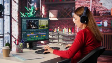 Video yapımcısı kadın, zaman çizgisi düzenleme ve renk derecelendirme arasında çift monitörlü bir video düzenliyor. Profesyonel editör teknolojik araçlar ve yazılımlar kullanır. Kamera B.