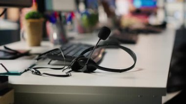 Müşteri destekli iş yerlerinde kullanılan mikrofonlu ses ekipmanı kulaklığı. Kapatın. İşçiler tarafından müşterilerle görüşmek için kullanılan çağrı merkezi ofis masasında mikrofonlu kulaklıklar.