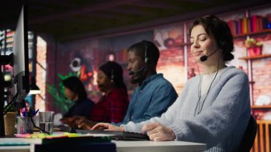 Müşteri sorunları dinleyen çalışanları destekliyor. Takım çalışması çağrı merkezi ajanları ofisin önünde yardımcı çözümler bulmak için kulaklık mikrofonuyla müşteri endişelerini çözüyor, kamera B