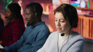 Müşteri desteği, gelen ve giden aramaları yöneten iş arkadaşları. Takım çalışması çağrı merkezi ajanları ofisin önünde müşteri sorularını cevaplamak için kulaklık kullanıyorlar. Kamera A.