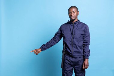 Afro-Amerikan devriye ajanı kamerada sol ya da sağ tarafı göstererek mavi arka planda ticari bir reklam için bir şey sunuyor. Güvenlik görevlisi bir yön gösteriyor..