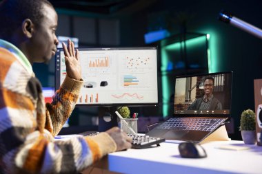 Siyahi adam görüntülü arama yapıyor ve iş bilgileri hakkında konuşuyor, aylık bütçe bakiyesini gözden geçiriyor ve uzaktan çalışıyor. Personel, bilgisayarda yapılan çevrimiçi toplantı sırasında konuşmaya odaklandı.