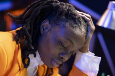 Sıkıntılı baş ağrısı çeken uzaktan kumandalı çalışanlar iş yüzünden bunalmış hissediyorlar. Stresli Afro-Amerikan serbest çalışanı evde çalışırken migren ağrısı çekiyor.
