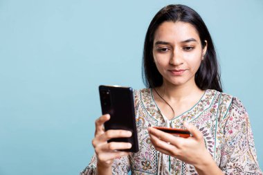 Neşeli kadın telefon kullanarak alışveriş sitesine ödeme metodu ekliyor. Stüdyodaki terfilerden faydalanıyor. Hintli kız internetten kredi kartıyla bir şeyler alıyor, cihaza veri yazıyor..