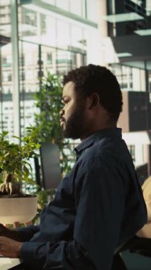 Modern ofisteki mali tabloları inceleyen dikey video çalışanı iş performans ölçümlerini analiz ediyor. Veri eğilimlerini ve stratejik görüşleri inceleyen profesyonel, kamera B