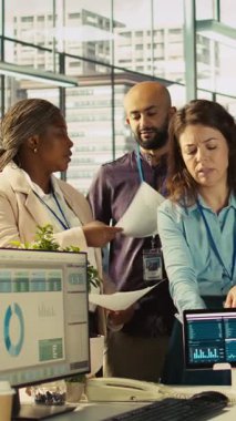 Süre dolmadan projeyi bitirmek için birlikte çalışan gülümseyen işçilerin dikey video portresi. Beyin fırtınası yapıyorlar. İyimser ofis memurlarından oluşan bir ekip görevlerde işbirliği yapıyor.