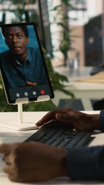 Video konferansında işçiyle sohbet eden dikey video yöneticisi, performans ve şirket büyümesi için hedefler belirliyor. İşçilerle telekonferans toplantısının yöneticisi. Tablet, kamera A kullanıyor.