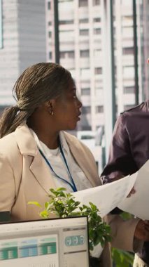 Ofisteki dikey video çalışanları beyin fırtınası yapıyor, finansal tabloları inceliyor, iş performans ölçümlerini analiz ediyorlar. İş yerinde çalışan iş arkadaşları sohbet ediyor, veri eğilimlerini inceliyor, kamera A