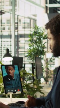 Video konferansında işçiyle sohbet eden dikey video yöneticisi, performans ve şirket büyümesi için hedefler belirliyor. İşçilerle telekonferans toplantısının yöneticisi tablet, kamera B kullanıyor.