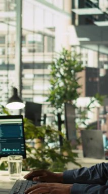 Ofisteki dikey video çalışanı dizüstü bilgisayardaki gelir rakamlarını yöneticiye gösteriyor. İşi bitirdikten sonra şirket istatistiksel numaralarını yöneticiye sunan muhasebeci, kamera B