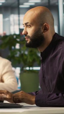 Finansal grafikleri inceleyen, kilit performans göstergelerini analiz eden dikey video Arap. Çalışma alanındaki Orta Doğulu çalışanlar veri eğilimlerini ve stratejik görüşleri inceliyor, kamera A