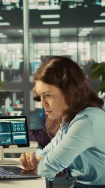 Raporları kontrol ettikten sonra finansal rakamları PC 'ye itham eden modern kurumun dikey video muhasebecisi. Modern ofiste çalışan odaklanmış iş kadını, çapraz veriler, kamera B