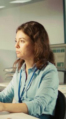 Bilgisayar masasında dikey video bürosu katibi belgeleri okuyor, görevleri çözüyor. Personel üyesi evrak belgelerindeki verileri analiz ediyor, istatistiksel bilgileri yorumluyor, kamera B