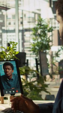 Ofisteki dikey video işçisi çevrimiçi video görüşmesi sırasında görev ilerlemesini denetleyen müdürle konuşuyor. Çalışan, uzaktan telekonferans sırasında yapılan işleri denetleyen denetleyici ile konuşuyor.