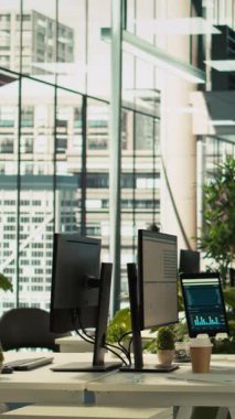 Dikey video Modern ofis çalışma masası bilgisayar monitörleri ile grafikler, grafikler ve veri analizleri gösteren, bitkiler ve şehir çevresi ile ilgili evrak ile çevrili, panning shot