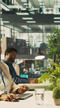 Finansal grafikleri incelerken, hareketli ofiste eğlenen dikey video çalışanları. Neşeli meslektaşlar çalışırken şakalarını paylaşıyor, veri eğilimlerini ve stratejik görüşleri inceliyor, kamera