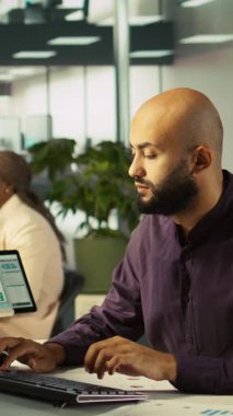 Bilgisayarla uğraşan modern başlangıç ajansındaki dikey video muhasebecisi, müdürümün raporları kontrol etmesini isterken araya girdi. Ofiste çalışan bir işadamı. Amirinin görevi evrakları karşılaştırmak.