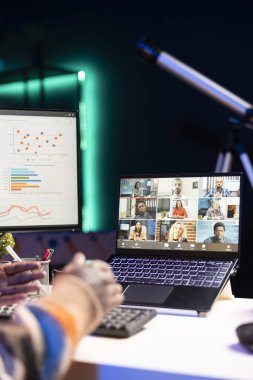 Afrikalı Amerikalı serbest çalışan erkek müşterilerle bilgisayar başında sanal görüşme görüşmelerine katılıyor, evde çalışıyor ve gelir istatistikleri hakkında görüşlerini paylaşıyor. Ekrana bakan ve video çağrısını dinleyen kişi.