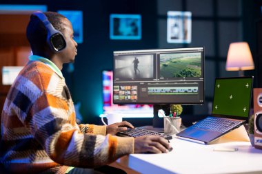 Görüntüleri ve çerçeveleri düzenlemek için renk düzeltmesi üzerinde çalışan, yeşil ekranın yanında kurgu üzerinde görsel efektler yaratan kameraman. Freelancer içerik düzenleyici bilgisayar yazılımındaki klipleri düzenliyor.