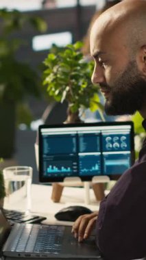 Görevdeki dikey video çalışanı laptopa bakarken başarıyı kutluyor ve başarılı sonuçlardan duyduğu heyecanı dile getiriyor. Adam olumlu iş başarısından mutlu, kamera A