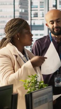 Süre dolmadan projeyi bitirmek için birlikte çalışan gülümseyen işçilerin dikey video portresi. Beyin fırtınası yapıyorlar. İyimser ofis memurlarından oluşan bir ekip görevlerde işbirliği yapıyor.