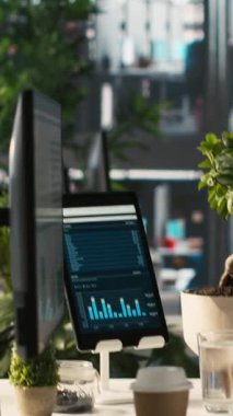 Ofis masasında şirketin kârlı performans ölçümlerinin finansal grafiklerini gösteren dikey video ekranı. PC ekranındaki veri analizleri şirketlerin iş gelirlerini gösteriyor KPI 'ler, çekimler