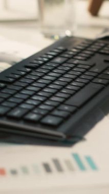 Dikey video modern çalışma alanı analitik veri belgeleriyle dolu parlak ofis ortamında saksı bitkileriyle birlikte. Ekranda gösterilen dijital istatistik çizelgeleriyle birlikte masadaki tableti kapat