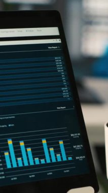 Şirket kârının performans ölçümlerinin finansal grafiklerini gösteren tablet ekranın dikey görüntüsünü kapat. KPI 'lerin şirket gelirlerini gösteren aygıt üzerindeki veri analizleri