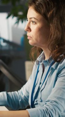 Bilgisayar masasında dikey video bürosu katibi belgeleri okuyor, görevleri çözüyor. Personel üyesi evrak belgelerindeki verileri analiz ediyor, istatistiksel bilgileri yorumluyor, kamera A