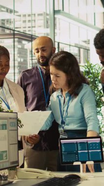 Ofisteki evrak işlerindeki gelir rakamlarına bakan gülümseyen iş arkadaşlarının dikey videosu. Mutlu muhasebeci ekibi, işi bitirmeden önce şirketin istatistiksel rakamlarını karşılaştırmaya odaklandı.