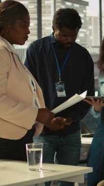 Belden aşağısı felçli ve ofis arkadaşları olan dikey video çalışanı beyin fırtınası yapıyor, finansal tabloları gözden geçiriyor, KPI 'ları analiz ediyor. Belden aşağısı felçli ve iş arkadaşları karşılaştırma yapıyor.