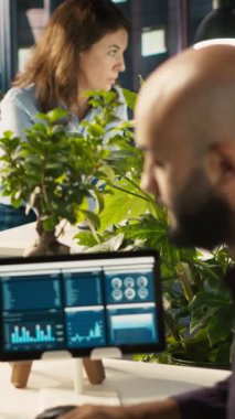 Ofisteki dikey video muhasebecisi PC 'ye finansal rakamlar girerek iş arkadaşlarına rapor veriyor. İş yerindeki Arap adam bilgisayardaki verileri karşılaştırıyor, iş arkadaşlarına belgeler veriyor, kamera A