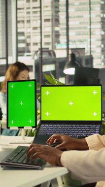 Şirketin idari işlerinde çalışan çalışanlar tarafından ofiste kullanılan dikey video Mockup tableti ve dizüstü bilgisayar. İşçi tarafından kullanılan masa üzerinde krom anahtar cihazları iş veri ölçümleri, kamera B