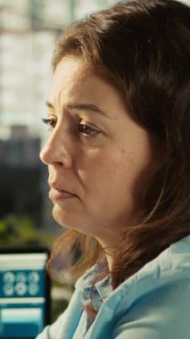 Ofisteki dikey video işçisi iş performans ölçümlerini incelerken bilgisayar masasında uyuyakalıyor. Yorgun bir kadın iş yerindeki mali tablolara bakarken uyukluyor.