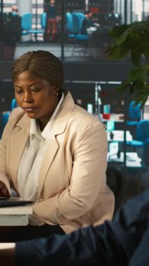 Ofisteki dikey video çalışanı dizüstü bilgisayardaki gelir rakamlarını yöneticiye gösteriyor. İşi bitirdikten sonra şirket istatistiksel numaralarını yöneticiye sunan muhasebeci, kamera A