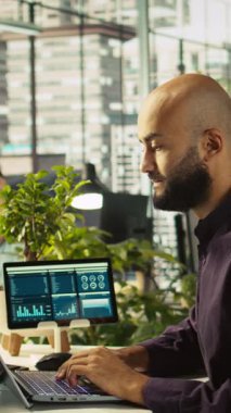 Ofisteki dikey video muhasebecisi PC 'ye finansal rakamlar girerek iş arkadaşlarına rapor veriyor. İş yerindeki Arap adam bilgisayardaki verileri karşılaştırıyor, çalışma arkadaşlarına belgeler veriyor, kamera B