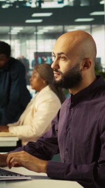 Dikey video ekibi çalışma arkadaşları masadaki bilgisayar ekranındaki veri tablolarını analiz ediyorlar. Masaüstü bilgisayarında hesap tablolarını tamamlayan çalışanlardan oluşan bir ekip, verileri giriyor ve analiz ediyor, kamera B