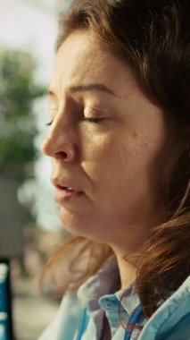 Dikey video, ofis masasındaki stresli çalışan bilgisayardaki belgeleri düzenlerken yorgun hissediyor. Bütün gün bilgisayardaki verileri girdikten sonra çok çalışan bir kadın yorgun düşmüş. Yorgunluk hissediyor. Kamera B.