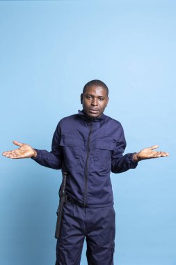 Afrikalı Amerikalı belirsiz koruma, stüdyoda omuz silkme, omuz silkme ya da bir konuda şüpheci olma hareketi bilmediğimi gösteriyor. Kameranın önünde güvensiz bir güvenlik ajanı var..
