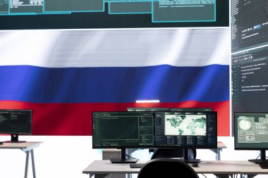 Büyük ekranda Rus bayrağı olan hükümet siber operasyon odası bilgi savaşı ve trollemeye odaklanıyor. Hackerların yanlış bilgi yayma ve kalabalığı kontrol etmedeki rolünü vurgulamak.